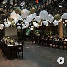 an indoor dining area with tables, chairs and paper lanterns hanging from the ceiling above