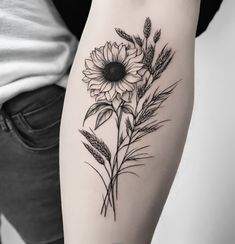 a black and white photo of a woman's arm with a sunflower tattoo on it