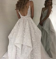 a woman standing in front of a mirror wearing a wedding dress with an open back