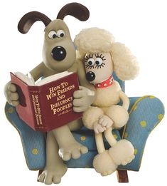 a dog sitting on top of a chair next to a stuffed animal reading a book