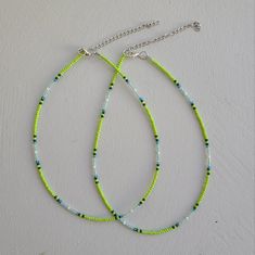 two green and blue beaded necklaces on a white surface