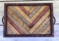 a square wooden tray with metal handles on a white painted wood wall, decorated with multicolored stripes