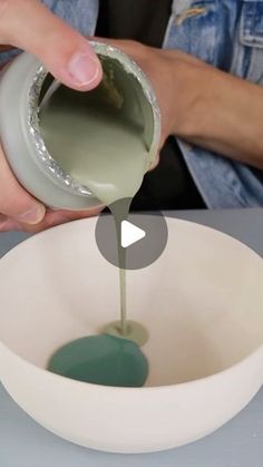 a person pouring green liquid into a white bowl