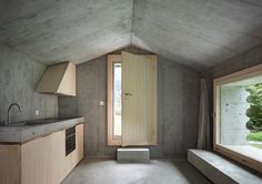 an empty kitchen with concrete walls and flooring is seen in this image from the window