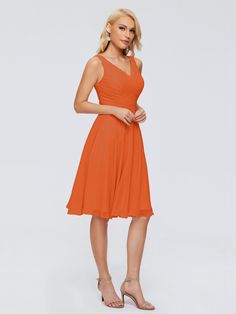 a woman in an orange dress posing for the camera with her hands on her hips