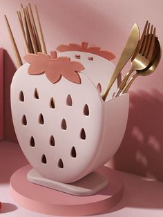 there are forks and spoons in the strawberry shaped container with utensils sticking out of it