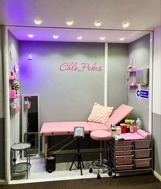 a salon room with pink furniture and lights on the walls, along with purple lighting