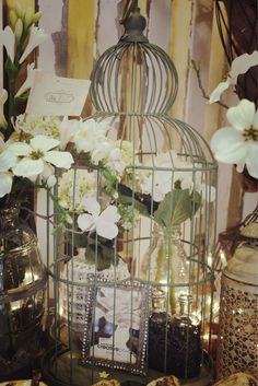 a birdcage filled with flowers sitting on top of a table next to other items