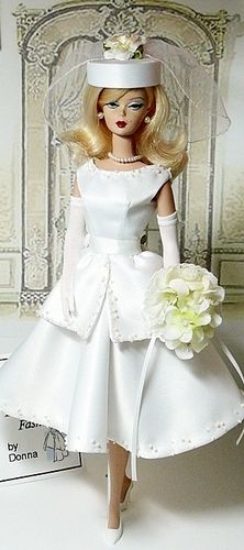 a doll in a white dress and hat