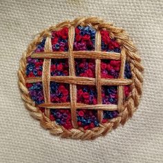 a close up of a woven object on a white surface with red, blue and purple crochet