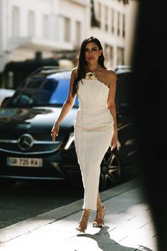 a woman in a white dress walking down the street