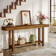 a wooden console table with two vases on it in front of a stair case