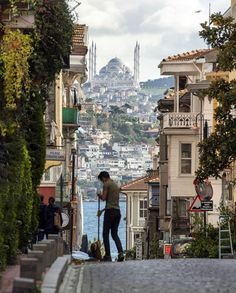 a man is standing on the sidewalk in front of some buildings with a city behind him