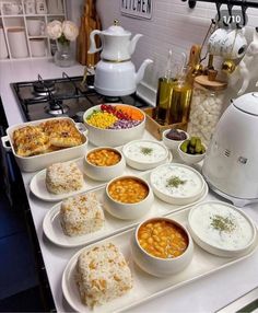 a kitchen counter topped with lots of bowls and plates filled with different types of food