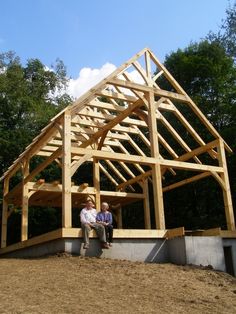 two people standing in front of a wooden frame structure on top of a dirt hill