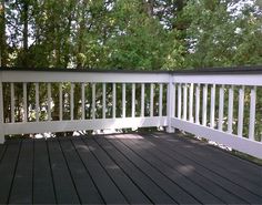 a deck with white railings and trees in the background