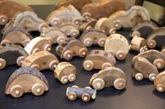 wooden toy cars are lined up on a black table top with other wood toys in the background