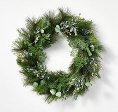 a christmas wreath hanging on the wall with greenery and balls around it's edges