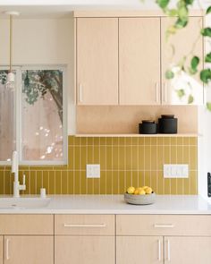 a bowl of lemons sits on the counter top in this modern, clean kitchen