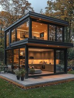 a small house with lots of windows in the middle of grass and some trees around it