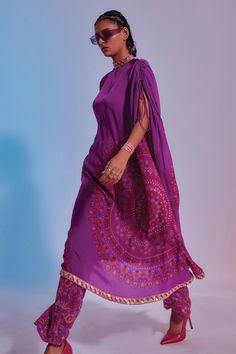 Purple kaftan tunic with geometric embellished and printed motifs all-over. Comes with straight pants.
Component: 2
Pattern: Print and Embellishment
Type Of Work: Geometric Motifs
Neckline: High
Fabric: Crepe Silk
Color: Purple
Other Details: 
Sleeves with tie up
Asymmetrical hem
Note: Hand accessory worn by the model is not for sale
Occasion: Resort - Aza Fashions Boho Attire, Kaftan Set, Kaftan Tunic, Printed Kaftan, Bandhani Dress, Long Kaftan, Silk Kaftan, Indian Fashion Designers, Pant Set