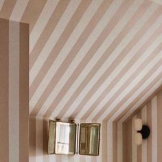 a bathroom with striped walls and two mirrors on the wall