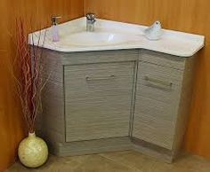 a white sink sitting next to a tall vase with flowers in it on top of a tiled floor