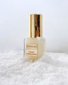 an open bottle of perfume sitting on top of snow covered ground with white powder around it