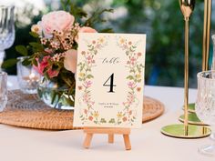 the table number is displayed on an easel next to some glasses and vases