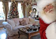 a man dressed as santa claus holding a christmas present in front of a living room filled with furniture