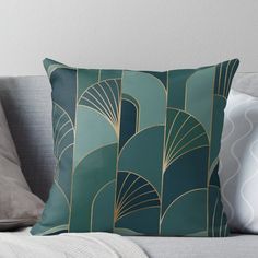 a green and gold art deco design throw pillow on a gray couch with white pillows