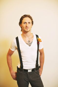 a man with suspenders and a flower in his hair is posing for the camera