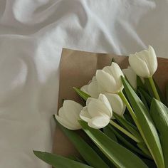 a bouquet of white tulips sitting on top of a brown paper bag