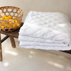 a basket full of lemons sitting on top of a wooden bench next to a blanket