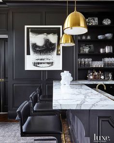 an image of a kitchen with black cabinets and white marble countertops in the center