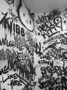 graffiti is on the wall next to a toilet in a public restroom with walls covered in black and white writing