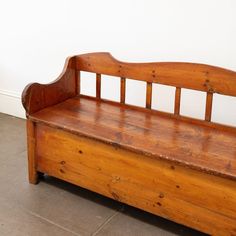 an old wooden bench sitting on top of a tile floor next to a white wall