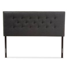 an upholstered headboard with studding on the top and bottom, in dark grey