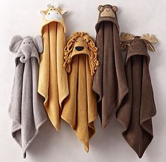 three towels with animals on them hanging from the wall, one is brown and one is beige