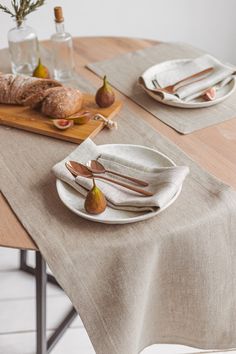 a person cutting bread on top of a wooden table with plates and utensils