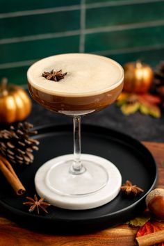 a drink sitting on top of a black plate next to an orange and cinnamon stick