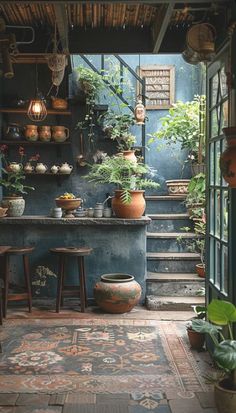 a room filled with lots of potted plants next to a stair case in front of a window