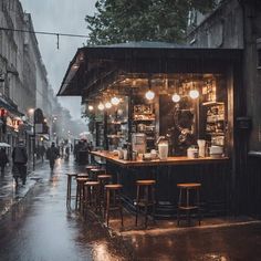 people walking down the street in the rain with umbrellas over their heads and tables