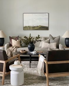 a living room with couches, chairs and a coffee table in front of a painting on the wall