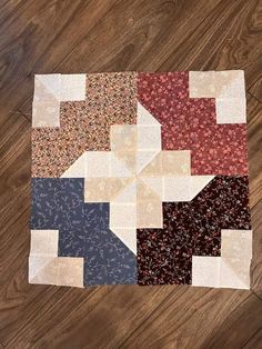 a piece of fabric is laying on top of a wooden floor with different colors and shapes