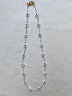 a blue beaded necklace with white pearls and a gold clasp on a white background