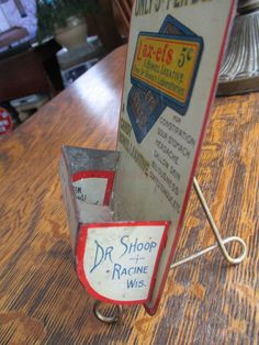 an old fashioned dr shop racing sign on a wooden table with a metal hook in front of it