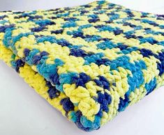 a blue and yellow crocheted blanket laying on top of a white table