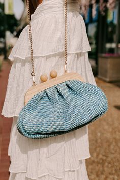 - Pull your look together with this sweet purse! Its woven design and wooden clasp make it the perfect for summer style. It easily elevates your OOTD giving it a laid-back yet chic vibe. - A fully lined pouch - Woven raffia material - Gold colored metal hardware - A magnetic wooden ball clasp closure - A removable chain strap - A zippered interior pocket Blue Summer Bags With Bamboo Handle, Blue Woven Clutch, Blue Rectangular Clutch For Vacation, Chic Woven Clutch For Spring, Chic Clutch For Summer Day Out, Chic Clutch For A Summer Day Out, Chic Summer Clutch For A Day Out, Trendy Summer Day Out Clutch, Blue Vacation Bag With Bamboo Handle