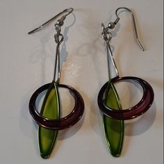 a pair of green and brown earrings on a white surface with silver hooks hanging from them